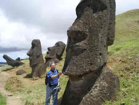 A man standing next to a large moai