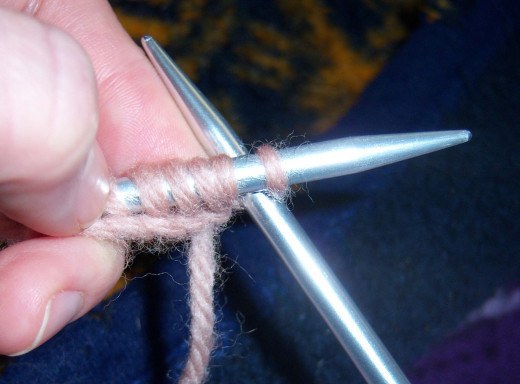 Slip the needle between stitches from front to back for a knit stitch.