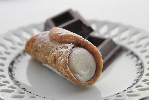 Presented on a plate, a cannolo is a popular pastry that's tubular in shape and filled with cream, often containing ricotta.  