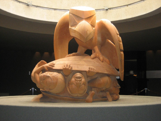 A depiction of the Haida creation story, where Raven opens an oyster shell on the beach to find the first Humans. Sculptor: Bill Reid. Canadian Museum of Civilization.