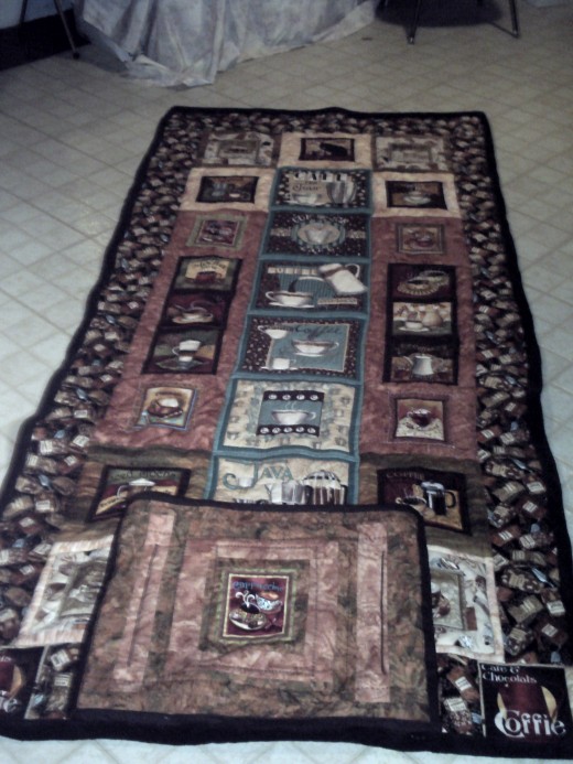 quillow finished by quilting stitch in the ditch and outlne quilting coffee cups and pots plus adding some steam and then pocket for quillow