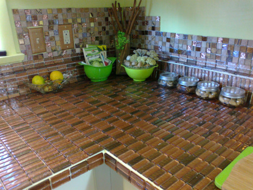 See how things look as you go along. Here you see natural stone back splash with a little bling worked in. The counter tile is slightly metalic in shades of copper and bronze. These tones are very neutral and work with a very wide variety of colors.