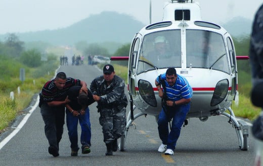 Federal Police escort drug cartel suspect from helicopter.