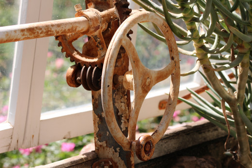 An antique hand-crank still serves to open the glass covers of the greenhouse.
