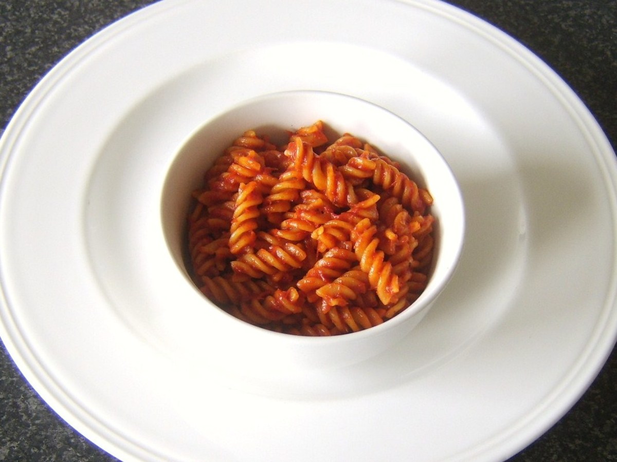 Fusilli pasta and sweet pepper and tomato sauce is spooned in to a serving bowl