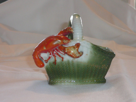 Lobster on a basket. Even though the patina is little worn off it is still rare and displays nicely. 3 3/4" x 3 1/2". $39. Rare.