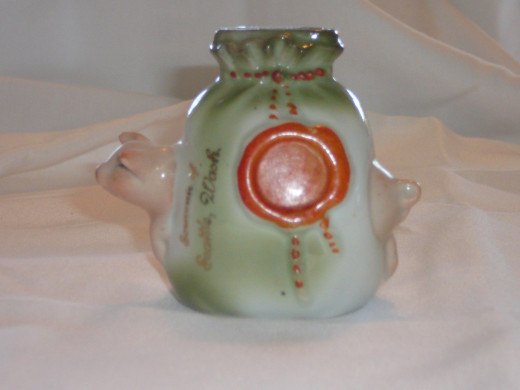 This piggy is caught trying to jump through a money bag. Souvenir Seattle Washington inscription added in America. Featured in "This little Piggy" its '92 price was $25. 3 3/8" x 3 1/2". Paid $68. Common.