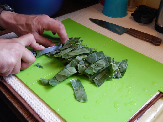 Cutting collard greens on a green cutting board.