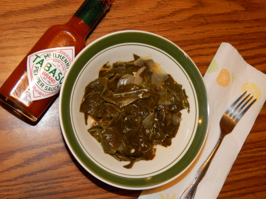 Bowl of fresh collard greens from the garden served with Tabasco sauce.