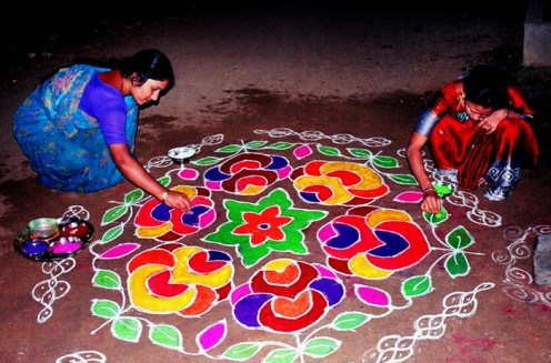  Women filling in vibrant colours on a RANGOLI in front of their doorway as a sign of welcome on Ugadi Day.
