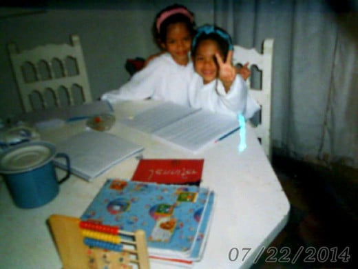 Me and my twin sister, Jennifer doing our homework in our school uniform, you can tell our uniform was all white and clean.