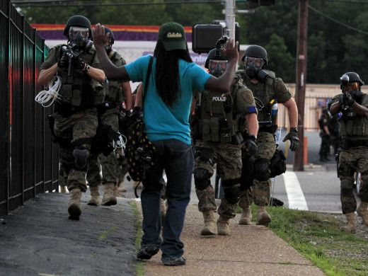 An African-American man during the Ferguson Riots on Monday, Aug. 11 faces an approaching SWAT team armed with assault weapons with his hands in the air. 