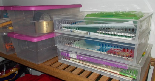 The homework trays are stacked next to the craft supply boxes in a closet.