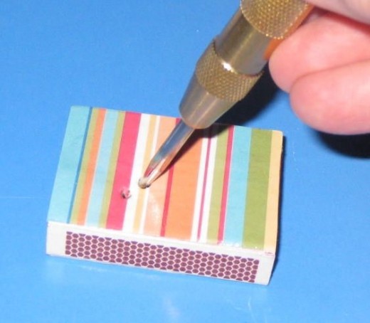 If you want to add beads or buttons to the top of the matchbox, use a hole punch to puncture the box. Be sure to line up the holes with the button holes.
