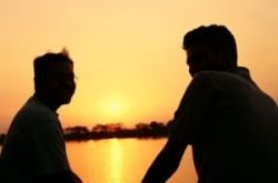Two friends comfortably talking with each other while watching a sunset