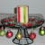 Black wire cake stand with ornaments hung around the edges, candy surrounds a candle in the middle.