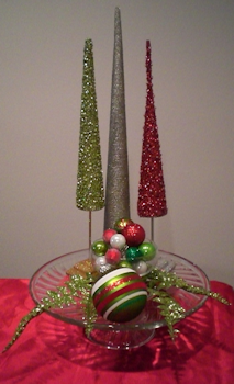 Three tree figurines in back, small bowl with ornaments in front, glitter fronds and large ornament accent.