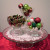 Martini glass and 1 small bowl filled with ornaments, larger bowl filled with garland, placed on a doily on the cake stand.