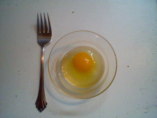 Crack the egg open and empty it into the little dish.