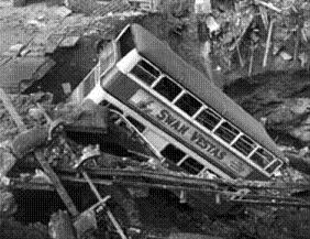 A bus fallen into a bomb crater.