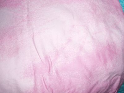 A plain white cotton pillowcase, dyed pink, then sprayed with a diluted bleach