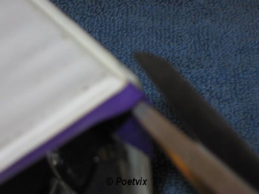 Use the scissors to snip the tape on the corners at the top and bottom of the binder. Fold it over. Repeat for the other inside cover.