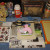 Materials: 1 cheap wooden picture frame, temporary tattoos, scrap paper left over from the first project, wide shimmer ribbon, thinner beige ribbon, skinny dark brown looped ribbon, one cross charm, fabric rosettes, glitter, stickers, 4 star studs, M Materials: 1 cheap wooden picture frame, temporary tattoos, scrap paper left over from the first project, wide shimmer ribbon, thinner beige ribbon, skinny dark brown looped ribbon, one cross charm, fabric rosettes, glitter, stickers, 4 star studs, M