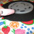 To make the bottom, simply glue the coffee can lid to a piece of felt. Then, glue the felt to the outer rim edge and trim it up. Cover that in ribbon at the very bottom. Snip the edges of the plastic in three spots to create some give. Apply a good a To make the bottom, simply glue the coffee can lid to a piece of felt. Then, glue the felt to the outer rim edge and trim it up. Cover that in ribbon at the very bottom. Snip the edges of the plastic in three spots to create some give. Apply a good a