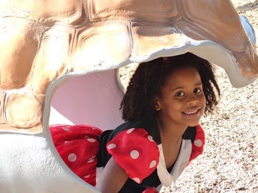 My beautiful granddaughter poses in the shell of a turtle at the zoo.