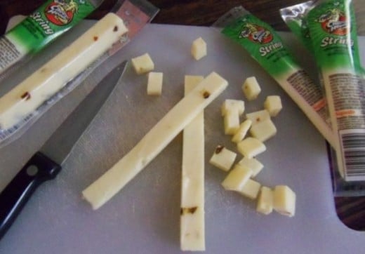 Cut the string cheese sticks in half, and  then into smaller pieces.