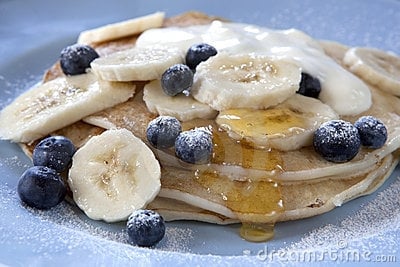 Blueberry pancakes with bananas and honey syrup.
